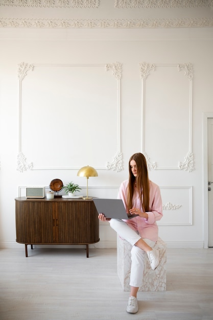 Foto gratuita mujer usando laptop en una habitación mínimamente decorada