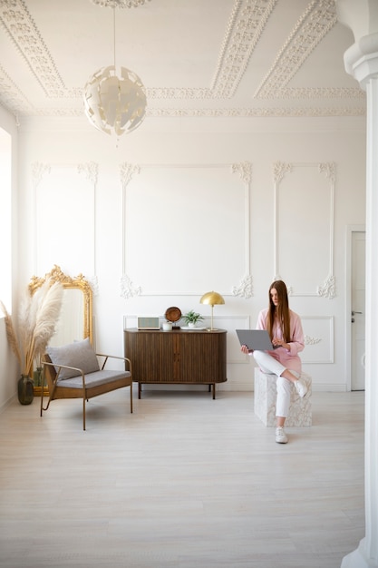 Mujer usando laptop en una habitación mínimamente decorada