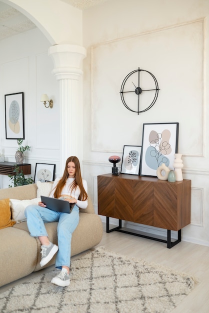 Mujer usando laptop en una habitación mínimamente decorada