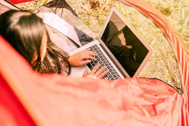 Mujer usando laptop mientras descansa en camping