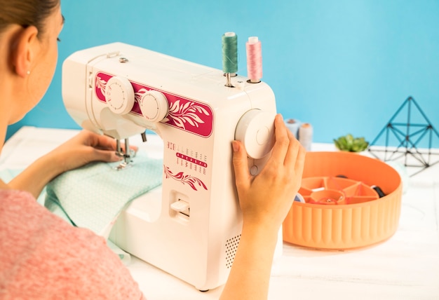 Mujer usando la máquina de coser sobre tela verde