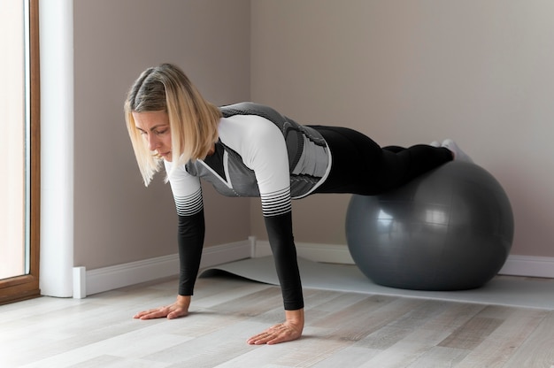 Foto gratuita mujer usando una pelota de fitness para su entrenamiento