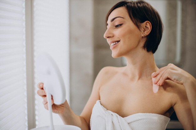 Mujer usando piedra gua sha en el spa