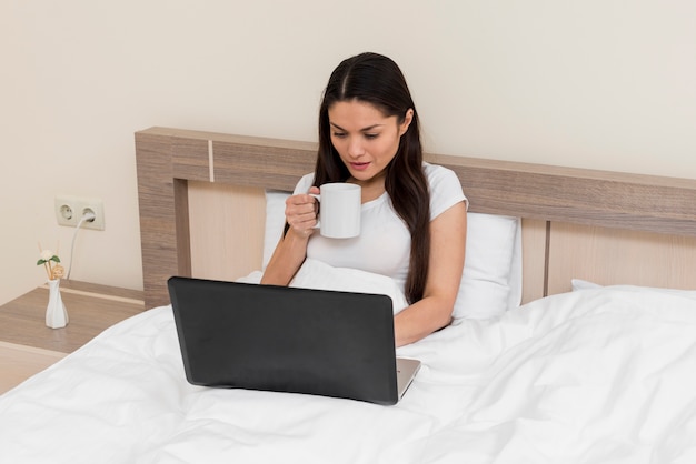 Mujer usando portátil en habitación de hotel