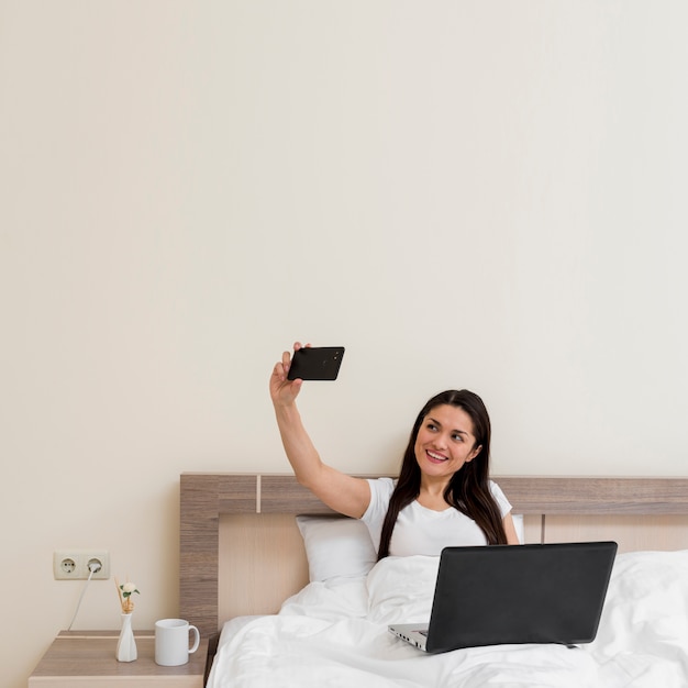 Mujer usando portátil en habitación de hotel