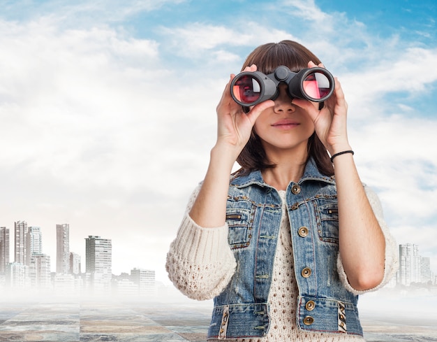 Mujer usando unos prismáticos con la ciudad de fondo