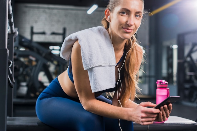 Foto gratuita mujer usando smartphone en gimnasio