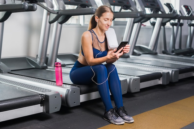 Foto gratuita mujer usando smartphone en gimnasio