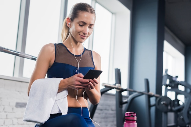 Foto gratuita mujer usando smartphone en gimnasio