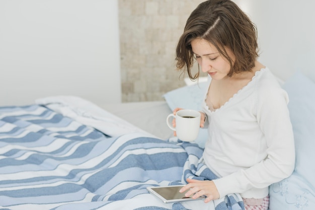 Mujer usando smartphone mientras está en la cama