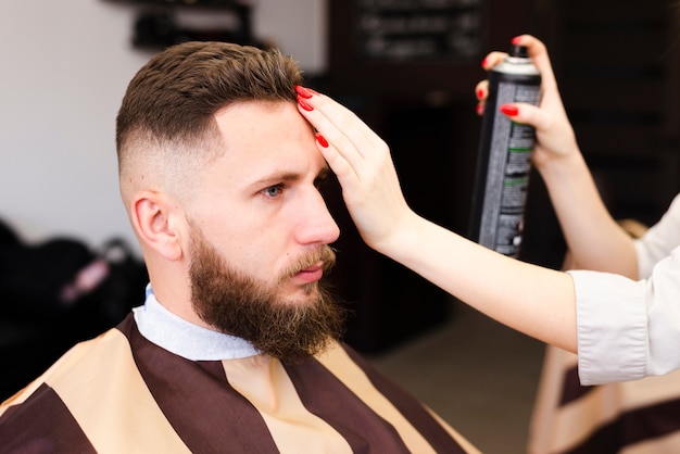 Mujer usando spray para el cabello en su cliente