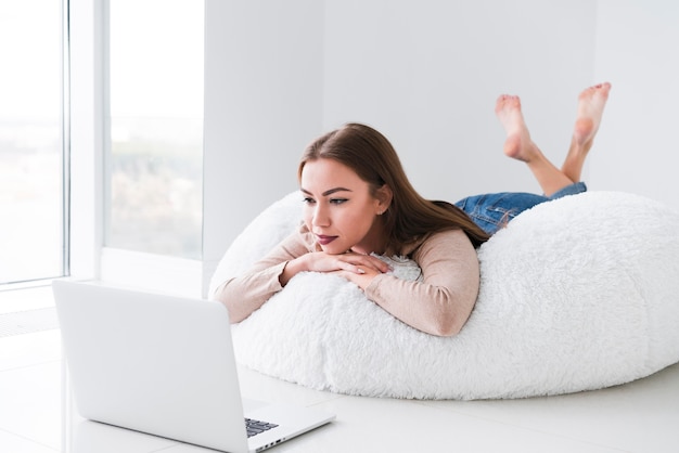 Mujer usando su computadora portátil y sentado en una bolsa de frijoles