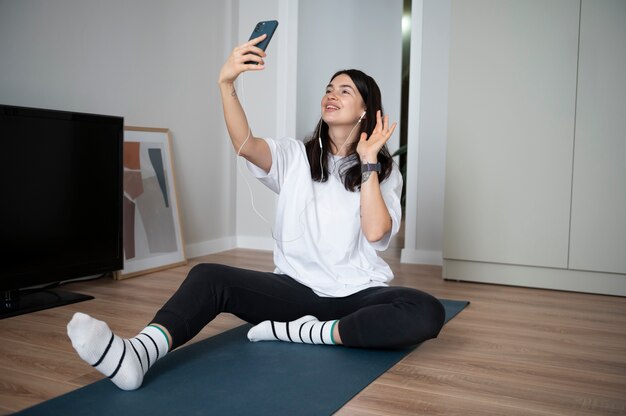 Mujer usando su teléfono inteligente en casa durante la cuarentena