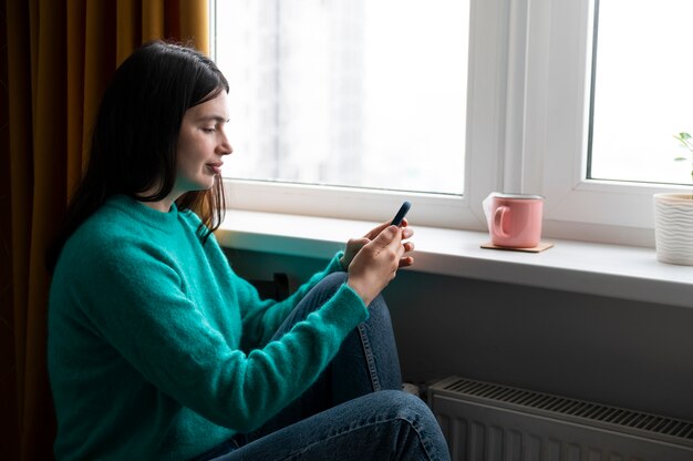 Mujer usando su teléfono inteligente en casa durante la cuarentena