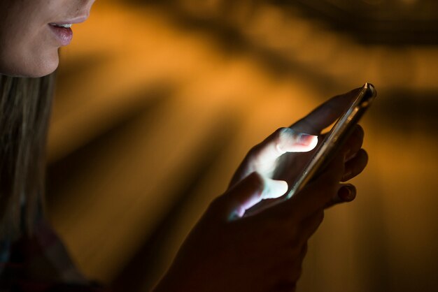 Mujer usando su teléfono inteligente, horizonte de la ciudad fondo la luz de la noche