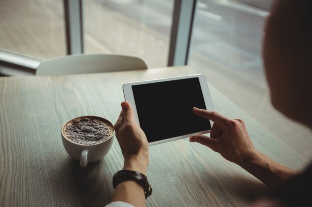Mujer usando tableta digital mientras toma una taza de café