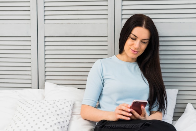 Mujer usando teléfono inteligente en la cama