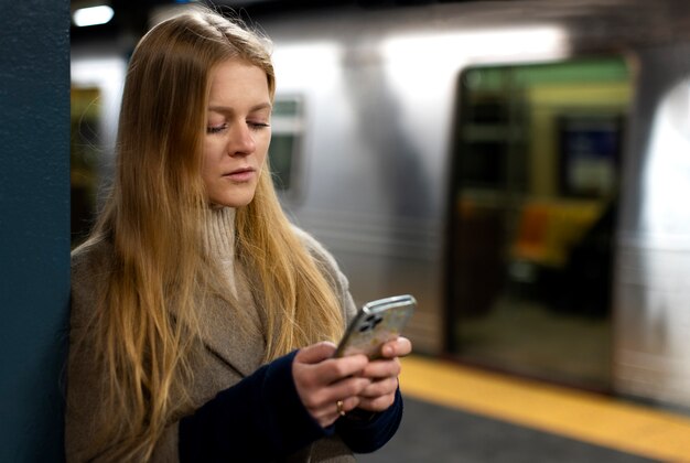 Mujer usando un teléfono inteligente mientras viaja en el metro de la ciudad