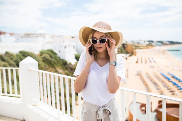 Mujer de vacaciones de verano con mensaje de texto sms de teléfono móvil fuera en la terraza del balcón