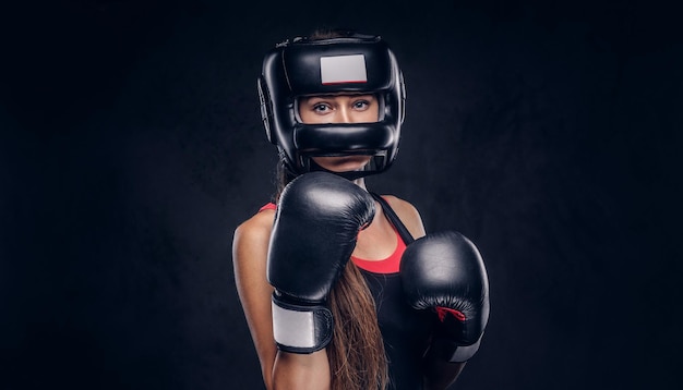 La mujer valiente está lista para pelear, lleva guantes de boxeador y casco protector.