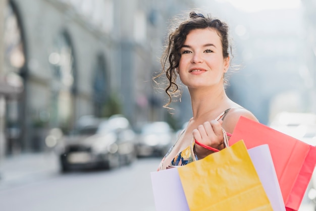 Mujer con varias bolsas de papel de compras felizmente