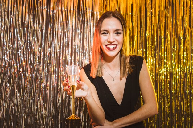 Mujer con vaso de champán en fiesta de año nuevo