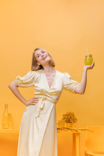 Mujer con vaso de limonada en escenario amarillo