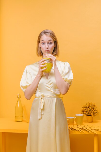 Mujer con vaso de limonada en un escenario amarillo