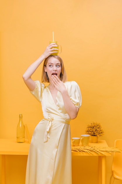 Mujer con vaso de limonada en un escenario amarillo