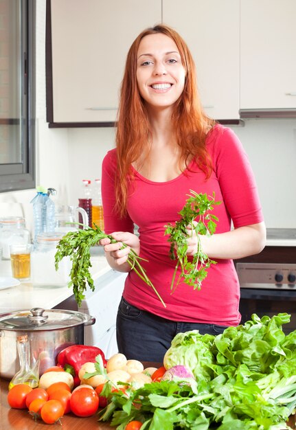 Mujer con verduras frescas y verduras en la cocina