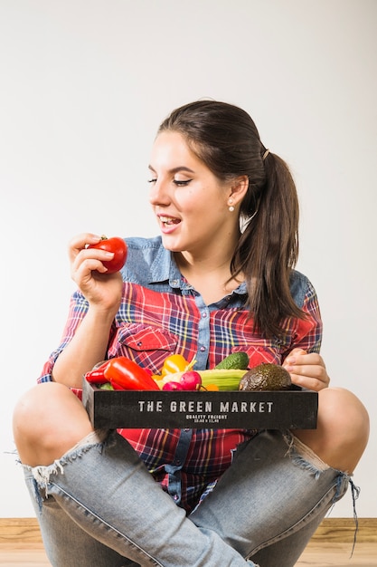 Mujer con verduras mirando tomate