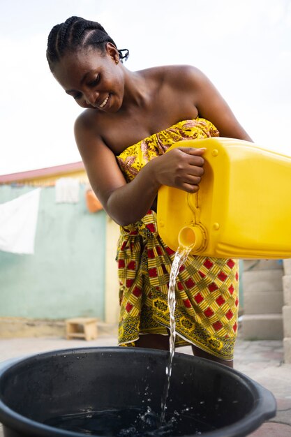 Mujer vertiendo agua de un recipiente amarillo