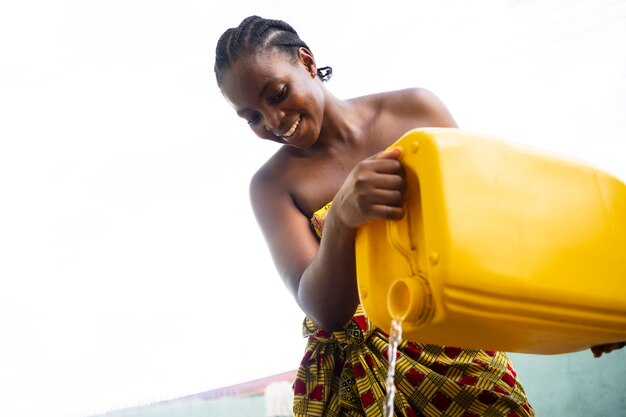 Mujer vertiendo agua de un recipiente amarillo