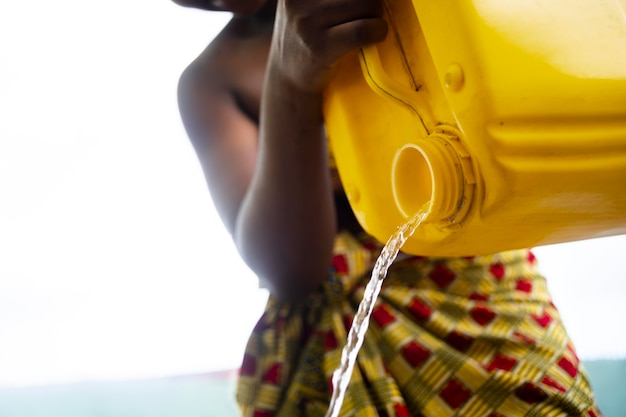 Mujer vertiendo agua de un recipiente amarillo