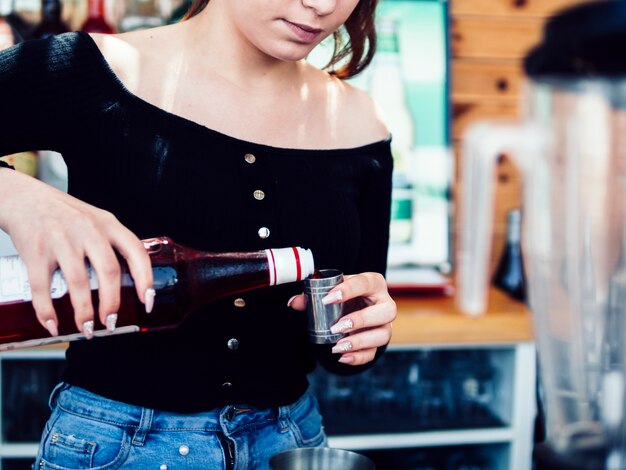 Mujer vertiendo alcohol en una taza medidora