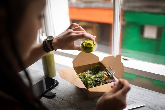 Mujer vertiendo salsa verde en una ensalada