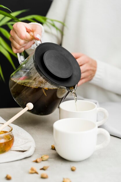 Mujer vertiendo té en una taza de tetera