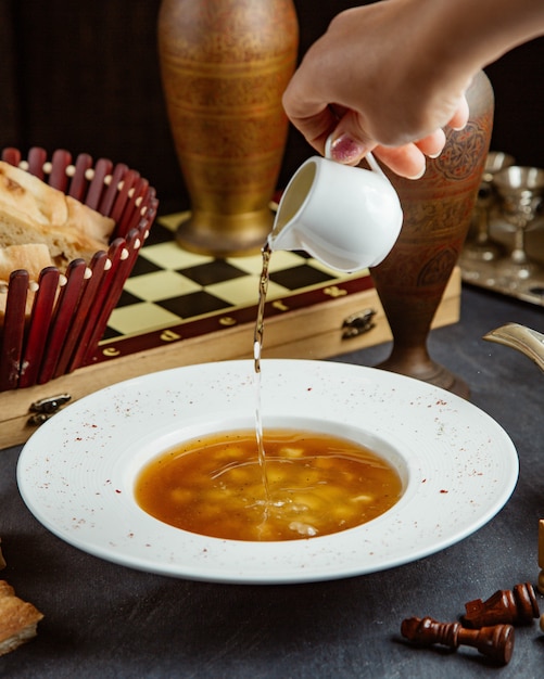 Foto gratuita mujer vertiendo vinagre en sopa de albóndigas dushbara