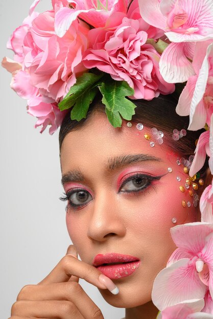 La mujer vestía maquillaje rosa y bellamente decorada con flores aisladas en blanco