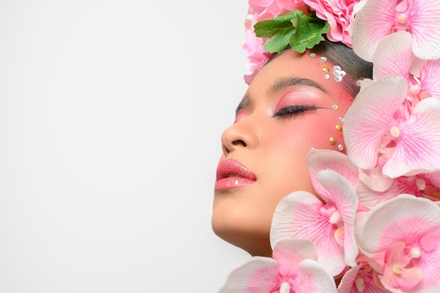 Foto gratuita la mujer vestía maquillaje rosa y bellamente decorada con flores aisladas en blanco