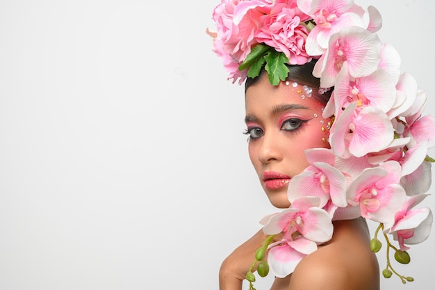 La mujer vestía maquillaje rosa y bellamente decorada con flores aisladas en blanco