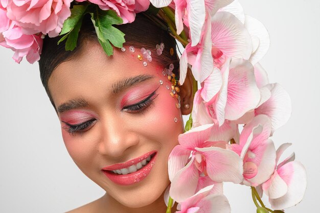 La mujer vestía maquillaje rosa y bellamente decorada con flores aisladas en blanco