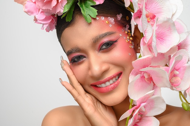 La mujer vestía maquillaje rosa y bellamente decorada con flores aisladas en blanco