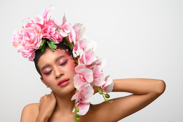 La mujer vestía maquillaje rosa y bellamente decorada con flores aisladas en blanco