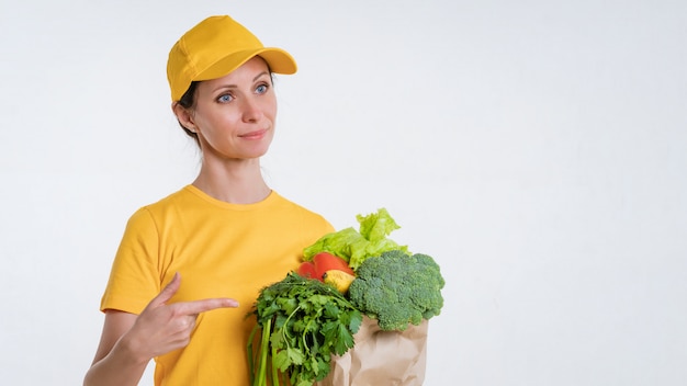 Una mujer vestida de amarillo, entregando un paquete de comida, sobre un fondo blanco