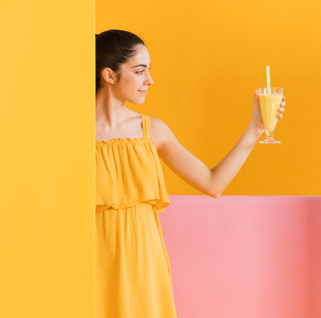 Mujer vestida de amarillo con un vaso de jugo