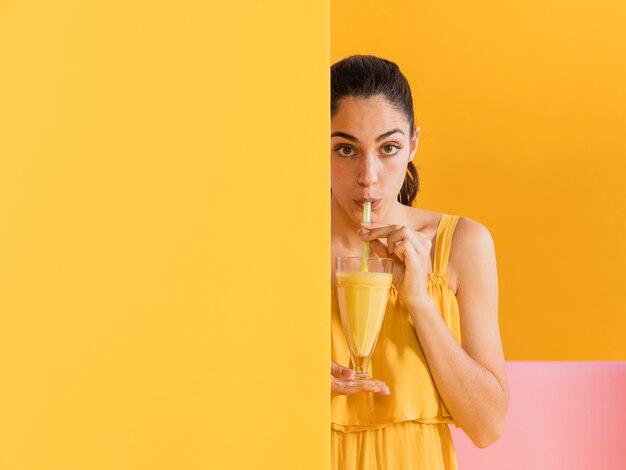 Mujer vestida de amarillo con un vaso de jugo