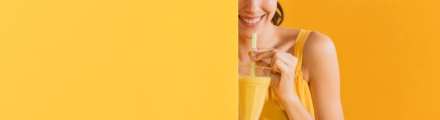 Mujer vestida de amarillo con un vaso de jugo
