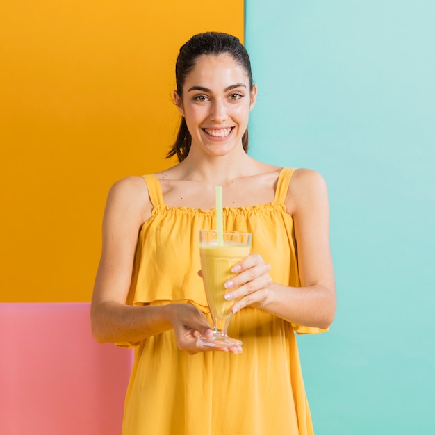 Mujer vestida de amarillo con un vaso de jugo