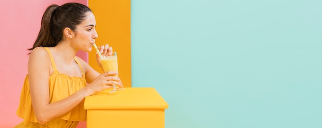 Foto gratuita mujer vestida de amarillo con un vaso de jugo